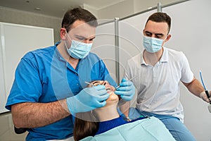 the dentist with the assistant carries out professional brushing of teeth of the patient.