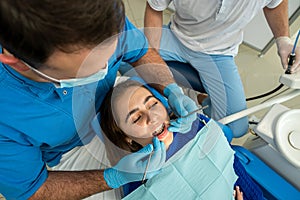 the dentist with the assistant carries out professional brushing of teeth of the patient.