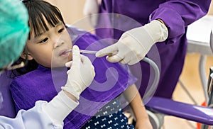 Dentist and assistant checking and cleaning asian girls teeth us