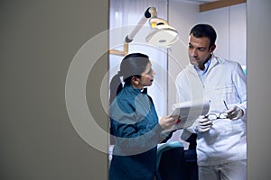 Dentist and assistant checking documents in dental studio