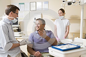 Dentist and assistant in exam room with man