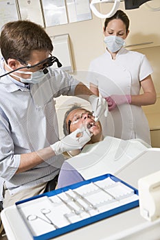 Dentist and assistant in exam room with man