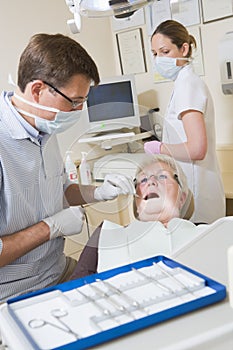 Dentist and assistant in exam room with woman