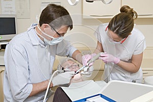 Dentist and assistant in exam room with woman