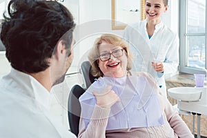 Dentist and assistant greeting senior patient