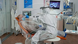 Dentist assistant in potective suit measuring patient temperature