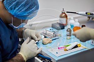 Dentist and assistant prepare dental implant on photo