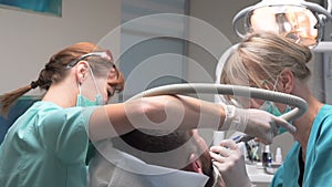 Dentist and assistant removing dental calculus from the teeth. Steadicam.