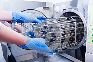 Dentist assistant`s hands get out sterilizing medical instruments from autoclave. Selective focus photo