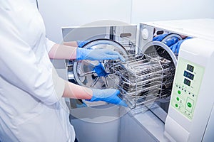 Dentist assistant`s hands get out sterilizing medical instruments from autoclave. Selective focus photo