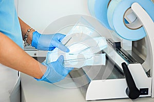 Dentist assistant`s hands holding packaged with vacuum packing machine medical instruments ready for sterilizing in
