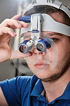 Dentist with binocular magnifying glasses working in dental clinic