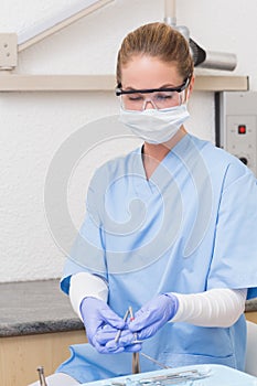 Dentist in blue scrubs holding dental tools