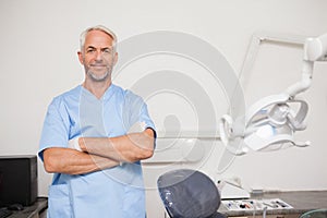 Dentist in blue scrubs smiling at camera