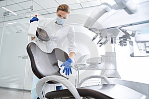 Dentist carefully sterilize the medical armchair inside a dental clinic photo
