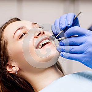 Dentist check-up teeth to young woman patient in clinic.