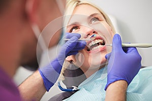 Dentist checking bracket at the braces on the female patient. Close-up. Real People.