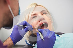 Dentist checking bracket at the braces on the female patient. Close-up. Real People.