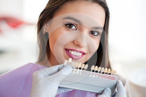 Dentist checking and selecting color of young woman`s teeth.