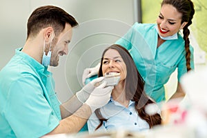 Dentist checking and selecting color of young woman`s teeth