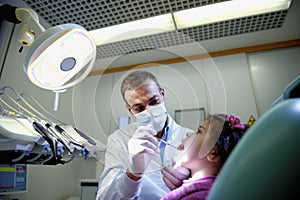 Dentist checking teeth of young girl lying on couch