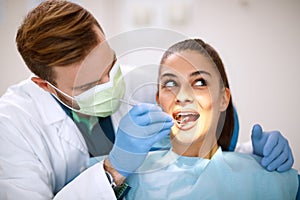 Dentist checking up girlâ€™s teeth with mirror