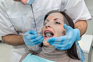 Dentist checking woman`s teeth with mirror during visit