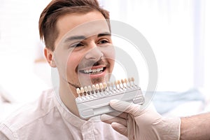 Dentist checking young man`s teeth color