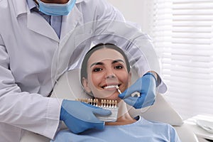 Dentist checking young woman`s teeth color in clinic