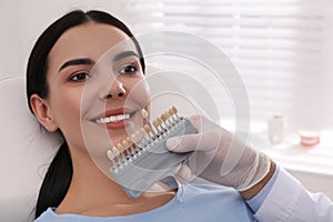 Dentist checking young woman`s teeth color in clinic