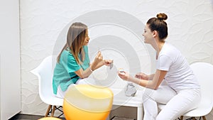 A dentist consulting her assistant regarding the colors of dental veneers