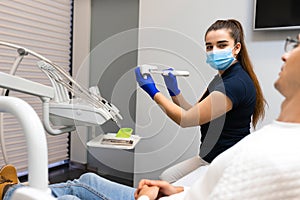 Dentist demonstrates to the patient on the jaw model how to clean the teeth with electric brush. Dental concept.