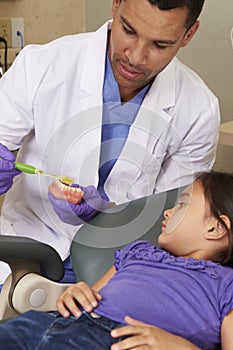 Dentist Demonstrating How To Brush Teeth To Young Female Patient