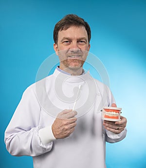 Dentist demonstrating a jaw model and a dental instrument. The notion of oral hygiene