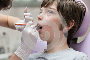 Dentist demonstrating young boy how to brush teeth photo
