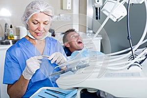 Dentist in dental clinic with patient behind