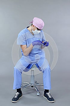 Dentist with dental instruments demonstrates typical unbalanced seated position at work