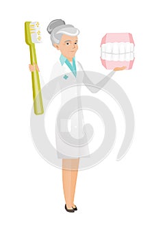 Dentist with dental jaw model and toothbrush.