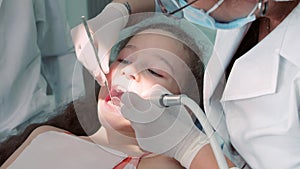 Dentist in the dental office, Woman Dentist Treating Teeth to little girl child Patient in Clinic. Female Professional