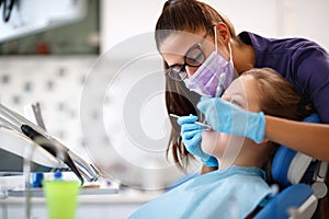 Dentist in dental ordination with girl in dental chair