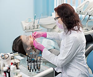 Dentist with dental tools - mirror and probe checking up patient teeth at dental clinic office. Medicine, dentistry