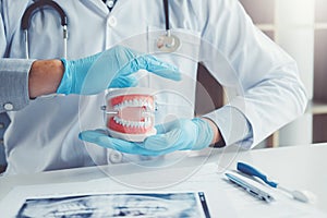 Dentist with denture learning how to teeth At dentistÃâs office photo