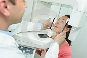 Dentist directing x-ray machine at dental clinic