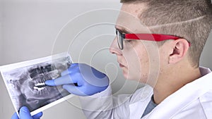 A dentist doctor examines a photograph of the teeth of a patient who has problems and teeth are inserted. The concept of research