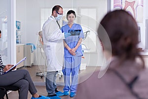 Dentist doctor holding teeth x-ray and nurse listening