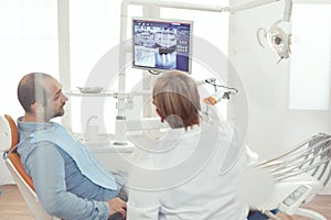 Dentist doctor and patient looking at digital teeh x-ray in stomatology hospital