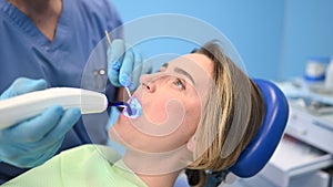 Dentist doctor using dental curing light equipment for filling, examining a patient`s teeth in dentistry office