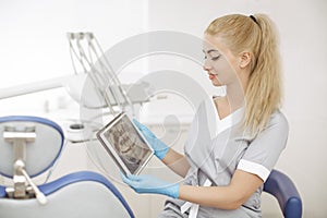 Dentist doctor using digital tablet against dental equipment.