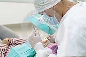 The dentist or doctor is wearing a white medical gown, mask and protective glasses in the background of the dentist& x27;s