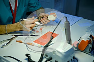 A dentist doctor is working on creating dentures. Tools for creating an artificial jaw on the prosthetist`s table